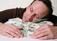 Mann umarmt sein Geld / iStock/Tatiana Morozova, sansara Mann schläft auf seinem Geld.