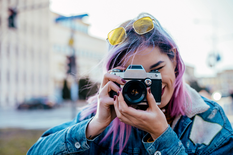 Close-up image of urban female photographer using camera.