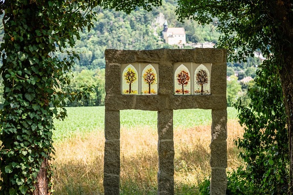 Dieses Fenster ist im gotischen Stil gehalten und man sieht im Hintergrund die Bergkirche von Pitten