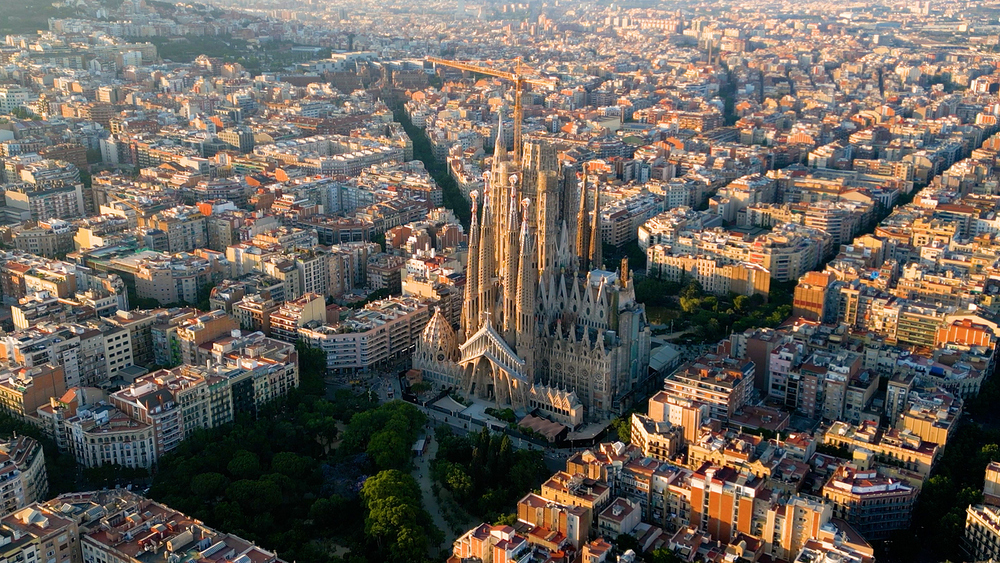 Basilica Sagrada Familia im Sonnenuntergang und die umliegende Stadt. / iStock/Vunav V Basilica Sagrada Familia im Sonnenuntergang und die umliegende Stadt.