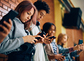 Group of teenagers using mobile phones in hallway at high school. / iStock/photo by drazen zigic, Drazen Zigic High school student and her friends using their smart phones in a hallway.